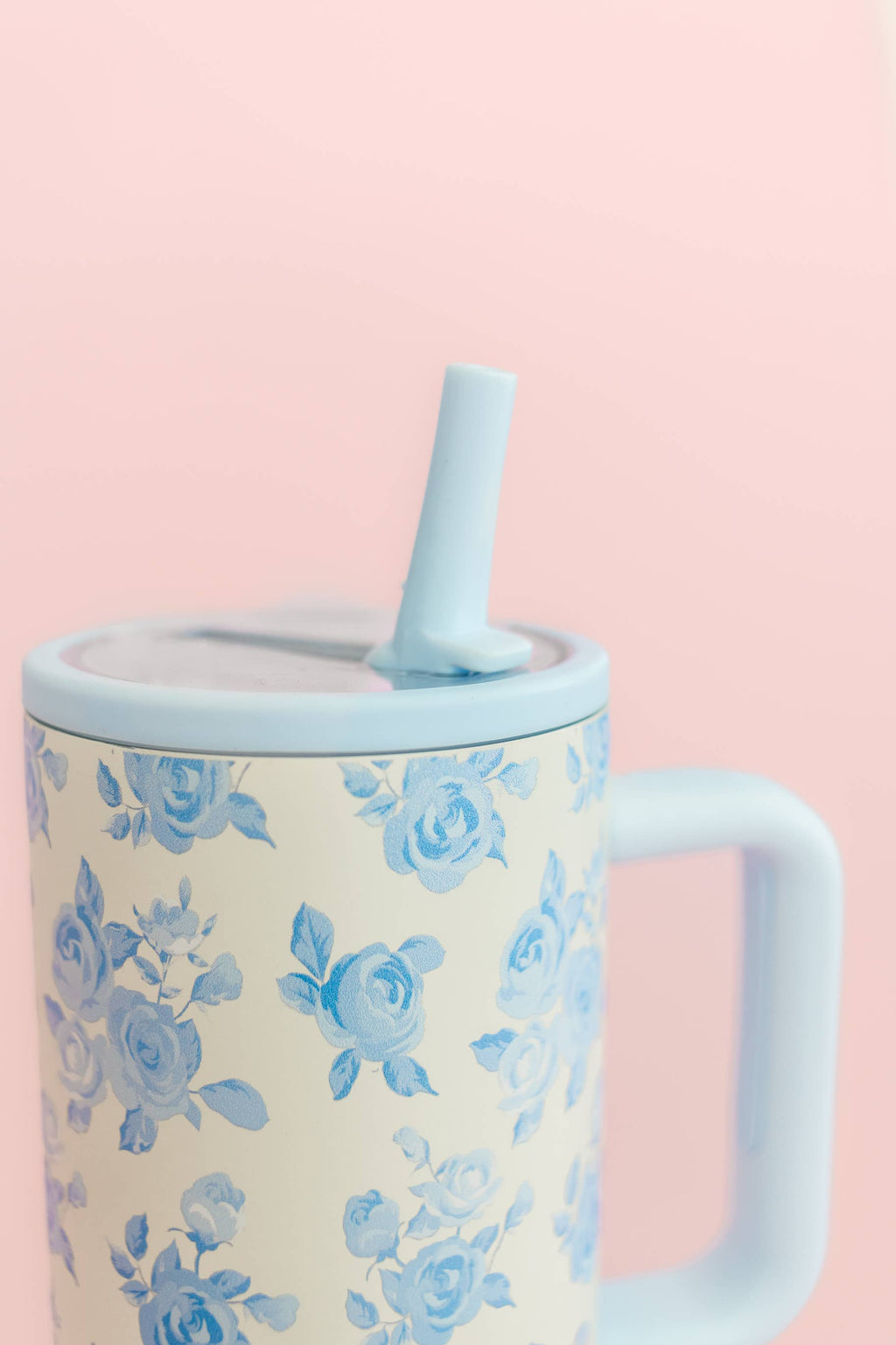 Mug with floral pattern and blue straw on a pink background