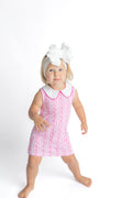 Young girl wearing a pink dress with white collar and a white headband on a white background