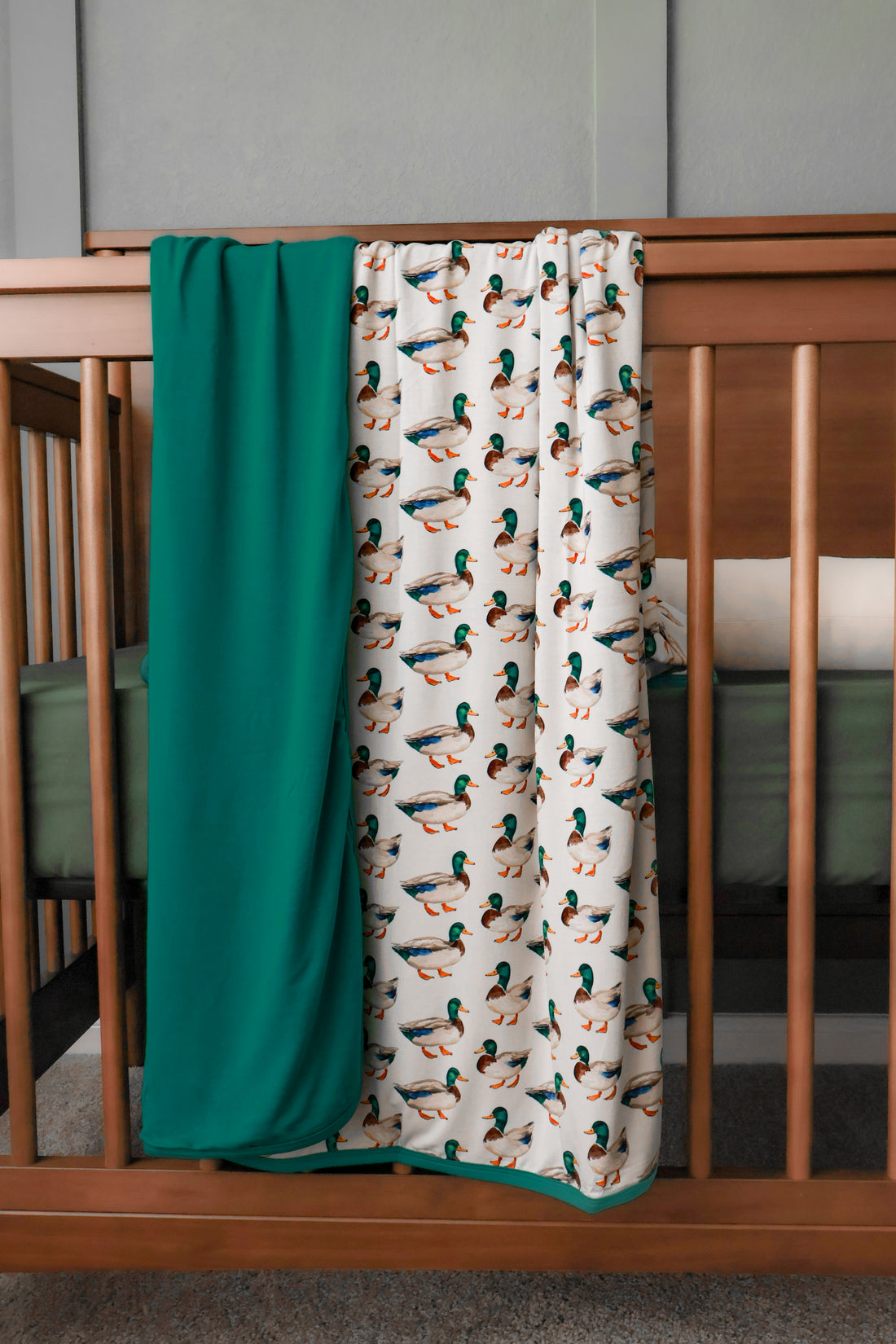 Crib with mallard duck print bamboo blanket. 