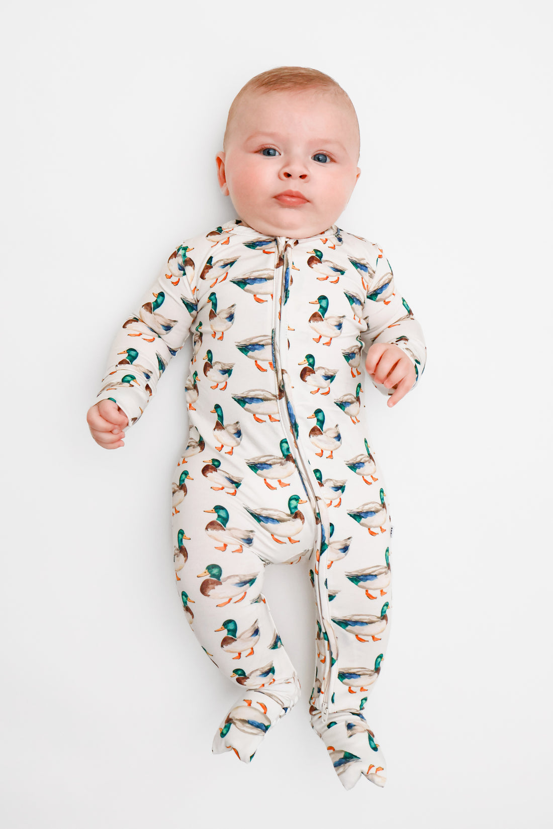 Baby wearing a bamboo romper with mallard duck pattern on a white background