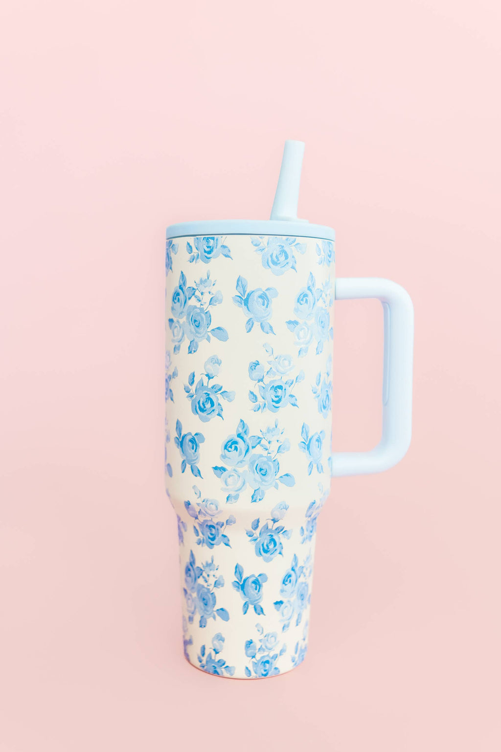 Floral-patterned tumbler with a handle on a pink background